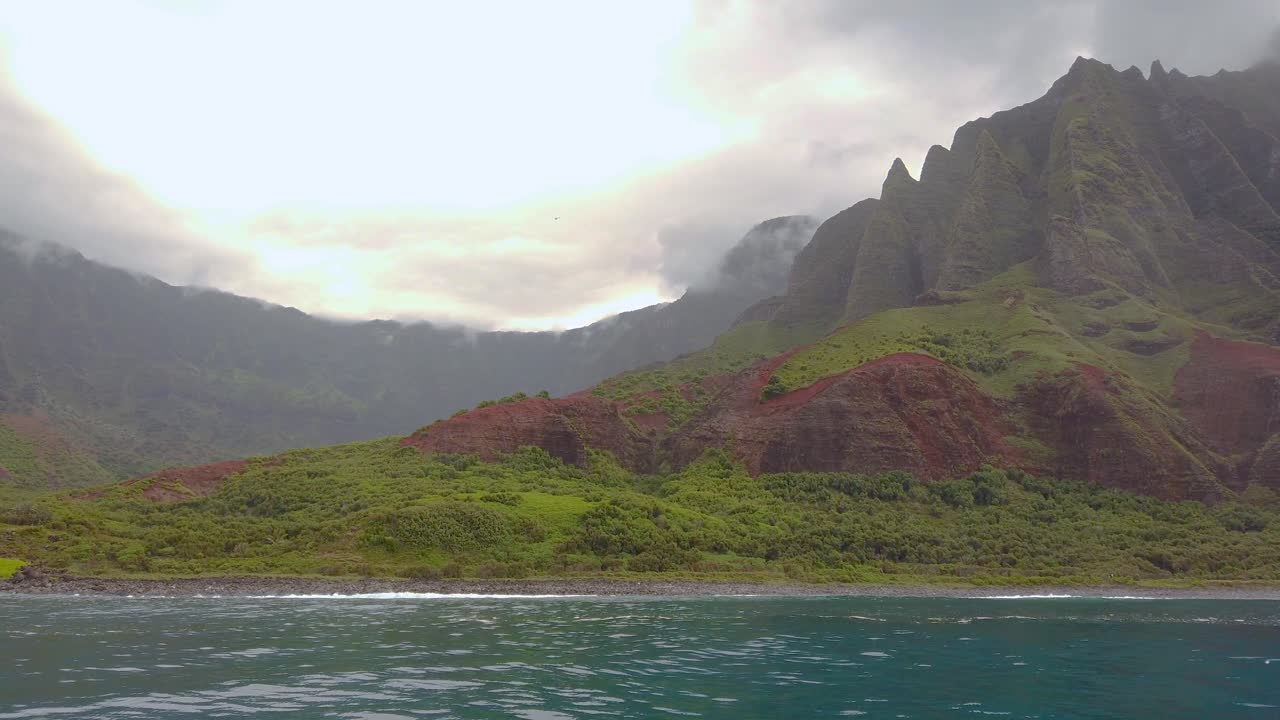 4K Hawaii Kauai Boating on ocean floating right to left from waves crashing at Na Pali Coast State Wilderness Park to mountains along shoreline
