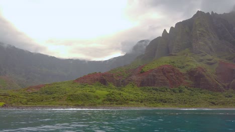 4k hawaii kauai boating on ocean floating right to left from waves crashing at na pali coast state wilderness park to mountains along shoreline