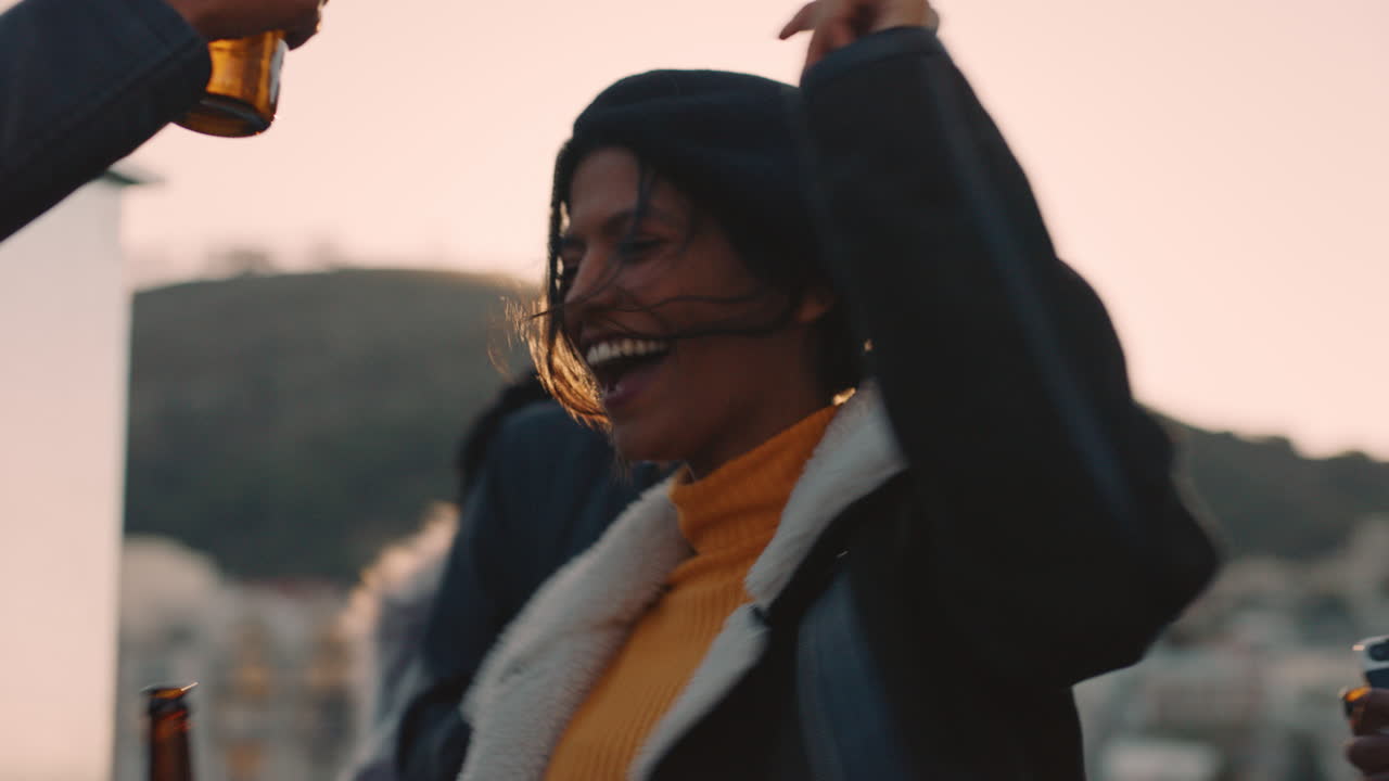 group of multiracial friends hanging out young mixed race woman dancing enjoying rooftop party at sunset drinking alcohol having fun on weekend celebration