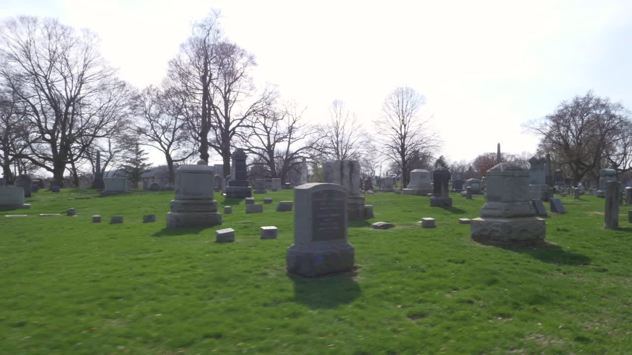 SLOW MOTION (48FPS): Driving slowly by an old mausoleum and rows of old headstones through a cemetery on a beautiful day