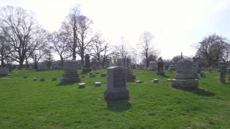 slow motion (48fps): driving slowly by an old mausoleum and rows of old headstones through a cemetery on a beautiful day