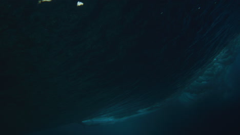 el agua del océano azul oscuro se eleva en vórtice a medida que el labio avanza con el surfista cortando hacia atrás a través de la parte superior, bajo el agua