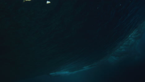 dark blue ocean water rises into vortex as lip goes forward with surfer cutting back across the top, underwater