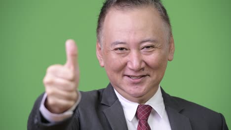 성숙한 일본인 사업가들이 엄지손가락을 올리고 있습니다.
