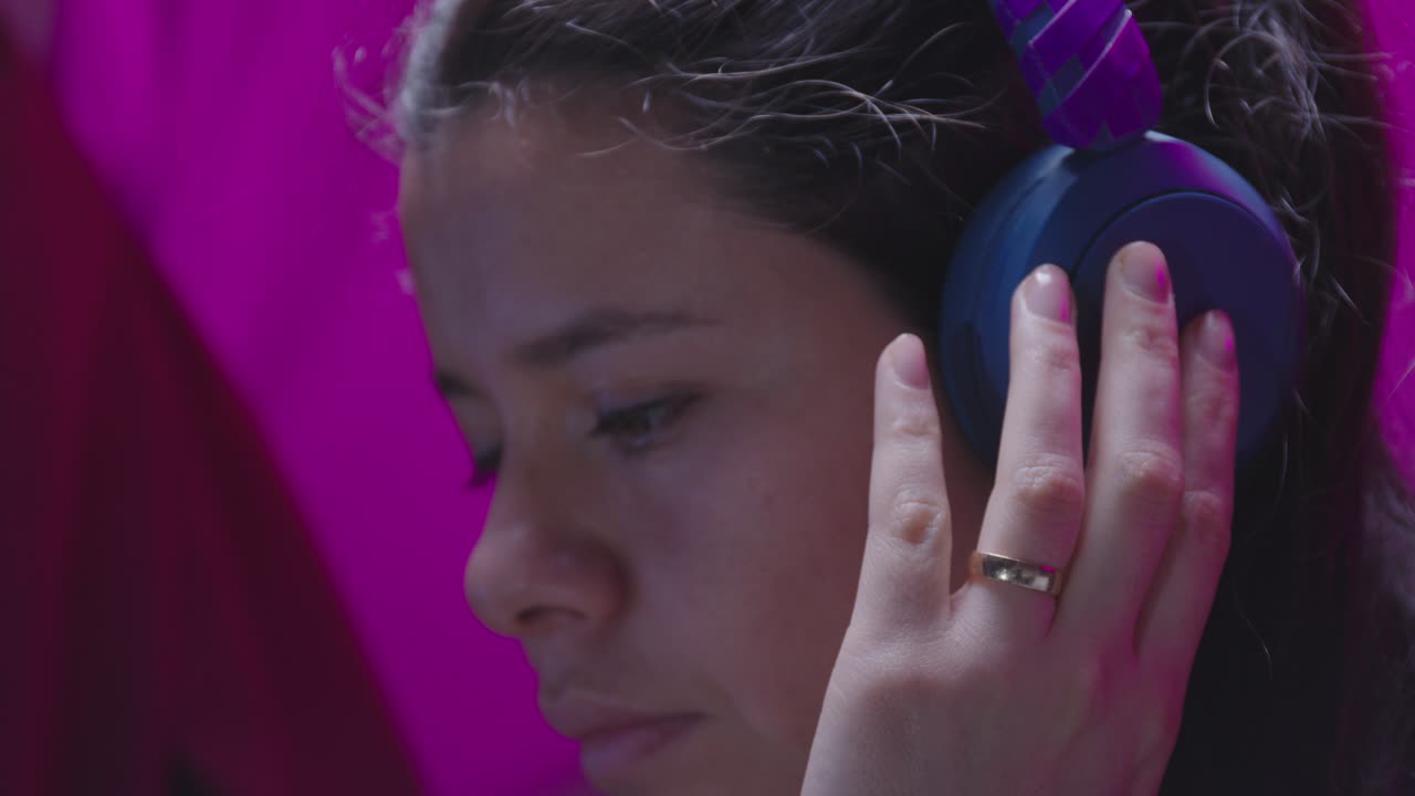 A young woman listens to something on her headphones and bursts into genuine, heartfelt laughter. This ungraded LOG footage is perfect for a joyful and authentic scene