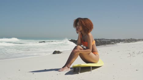 mujer afroamericana sentada en su tabla de surf