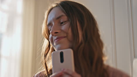 happy girl holding mobile phone in golden sunlight closeup. teenager in love