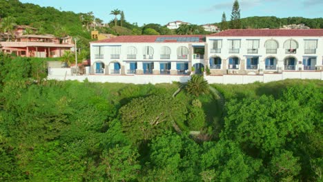 holiday resort houses on the green jungle hillside of buzios rio de janeiro, aerial drone fly above joao fernandes beach, brazilian landscape