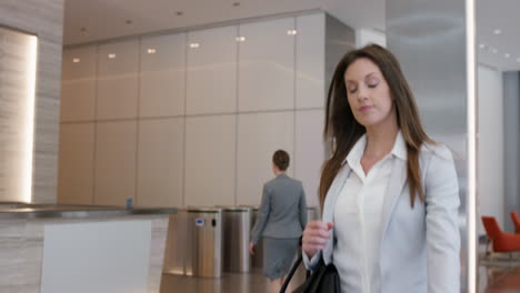 Attractive-successful-businesswoman-leaving-corporate-office-lobby-checking-smartwatch