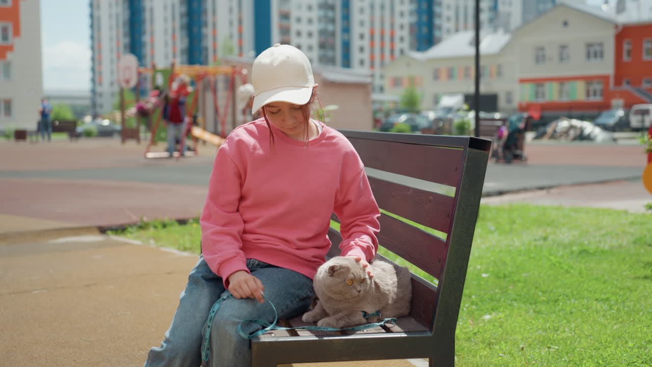 Young Child Relaxes With Tiny Pet Outdoors, Child Sitting Comfortably On Park Bench With Pet Nearby, Young Child Rests Along Bench In Tranquil Urban Park Area With Small Dog Nearby