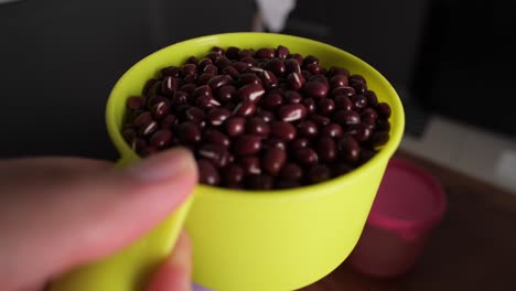 primer plano de frijoles rojos que se vierten del tazón mientras se prepara bubur kacang merah