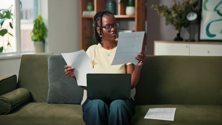 Woman working at home with laptop and documents