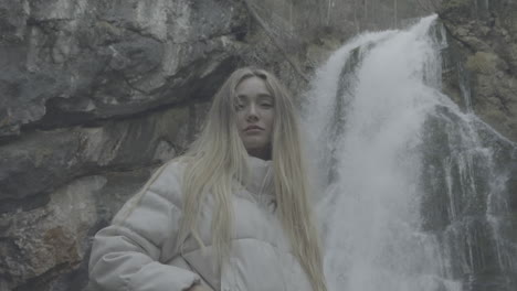 woman standing in front of a waterfall in a misty forest