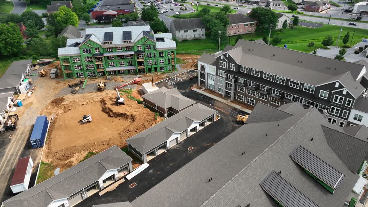 Construction site with new build apartment houses during building phase in American suburb city. Aerial view. Grey roofing tiles. Next step bricks for front facade