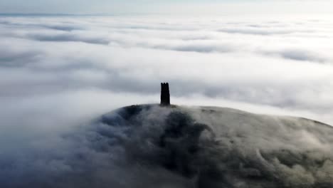 glastonbury tor, somerset mit nebel, der sich darüber erhebt