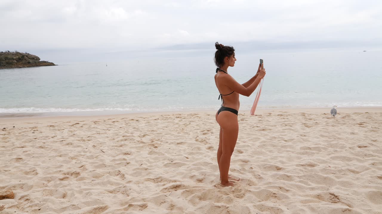 Donna sulla spiaggia che scatta una foto