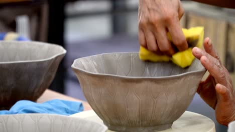 traditional pottery making, close up of potter's hands shaping a bowl on the spinning by clay