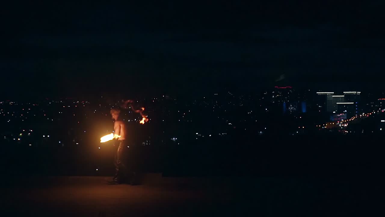 젊은 금발 남성이 큰 불의 흐름을 호흡하여 불의 공을 느린 동작으로  ⁇ 습니다.