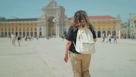 woman walking through lisbon's praca do comercio