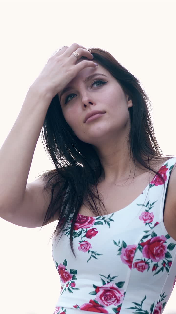 exciting close motion around brunette lady in coloured dress fixing long hair in summer windy weather