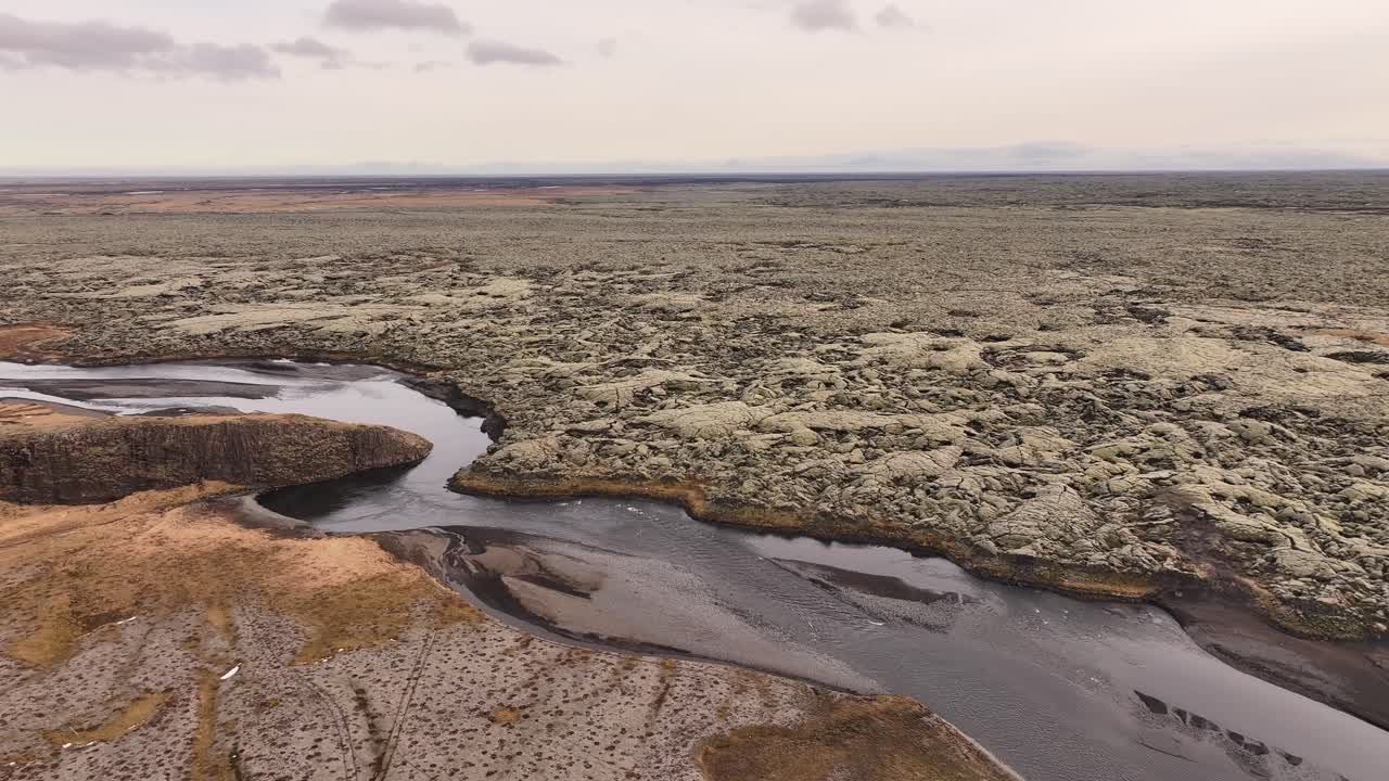 Aerial view of Fjaðrárgljúfur Canyon near Kirkjubæjarklaustur, Iceland, featuring a winding river through moss-covered volcanic cliffs under a soft, overcast sky.
