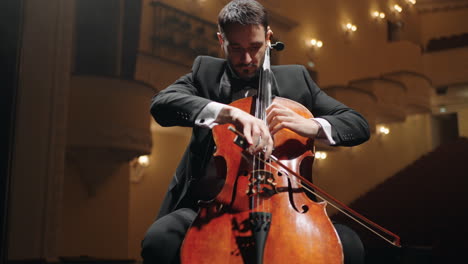 inspired cellist is playing violoncello on scene in old opera house rehearsal or concert of symphonic orchestra