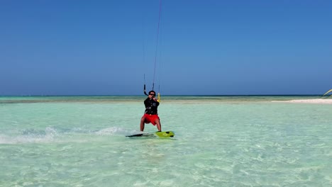 man kitesurf on turquoise caribbean sea from left to right near beach camp sandbank