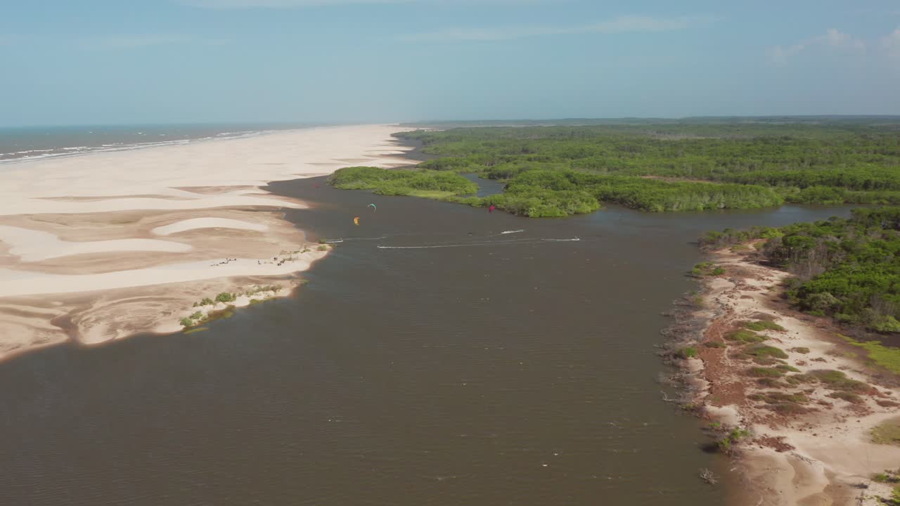 Aerial view of beach meeting river with kitesurfers