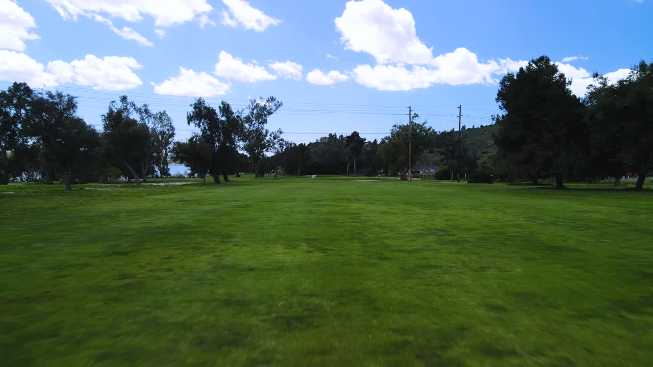 Aerial drone view flying low to the ground at a golf course on a cloudy day