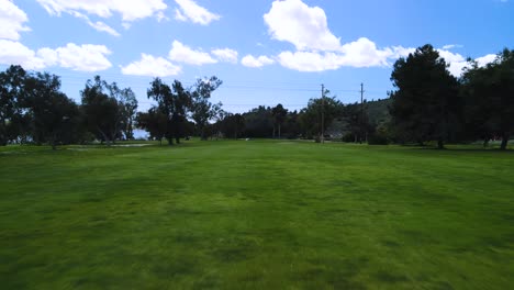 Vista-Aérea-De-Un-Dron-Volando-Bajo-Sobre-El-Suelo-En-Un-Campo-De-Golf-En-Un-Día-Nublado