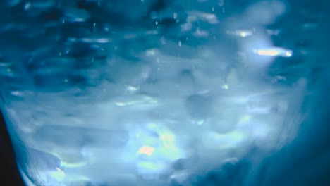 Eis-In-Einem-Klaren-Glas-Wasser,-Das-Bei-Steigender-Temperatur-Auf-Dem-Blauen-Hintergrund-Des-Kopierraums-Schmilzt