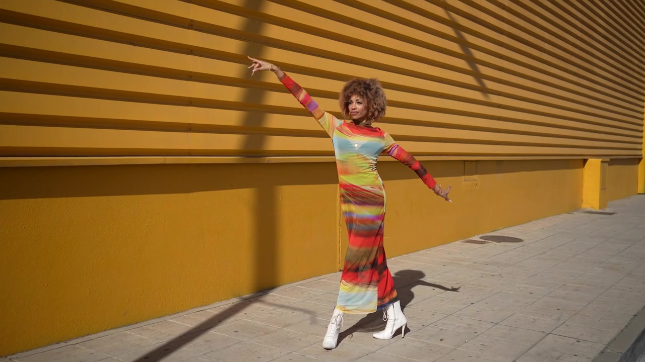 A chic and stylish model is strikingly posing against an eyecatching vibrant yellow wall