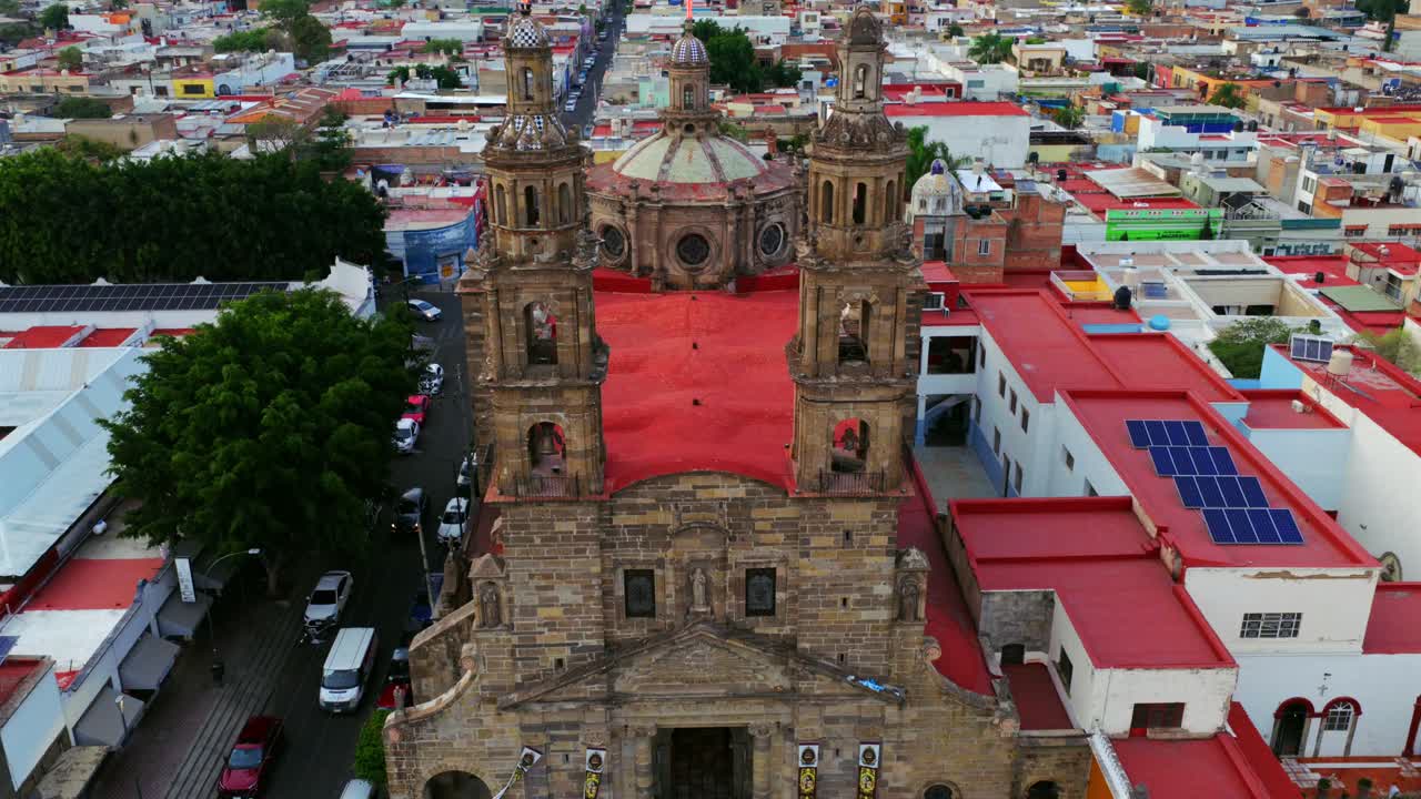 Slow motion aerial overlooking Dulce Nombre de Jesús Church facade, bell towers and red roof in Guadalajara, Jalisco, Mexico
