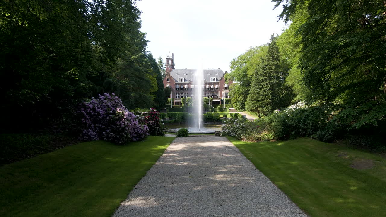 Niedrige Luftaufnahme in Richtung eines Brunnens vor einer schönen Villa.