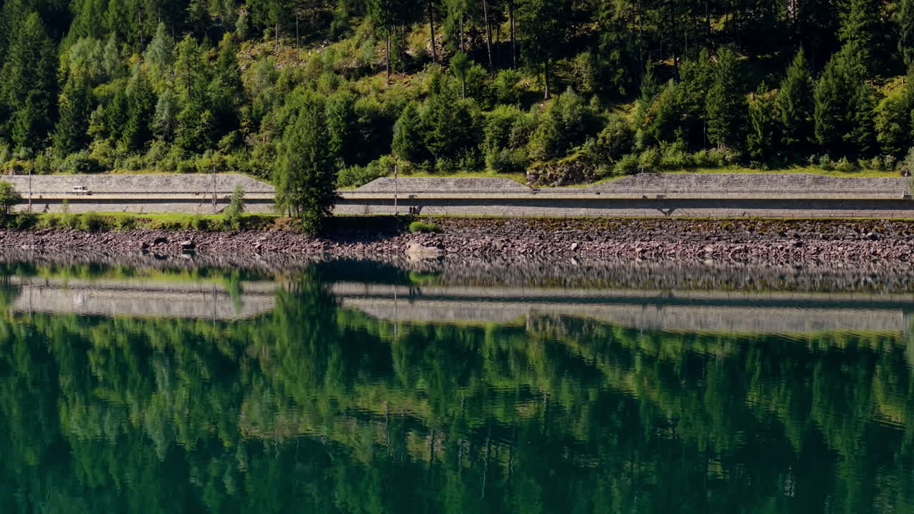 Serene lake with a road and forest reflection in Switzerland