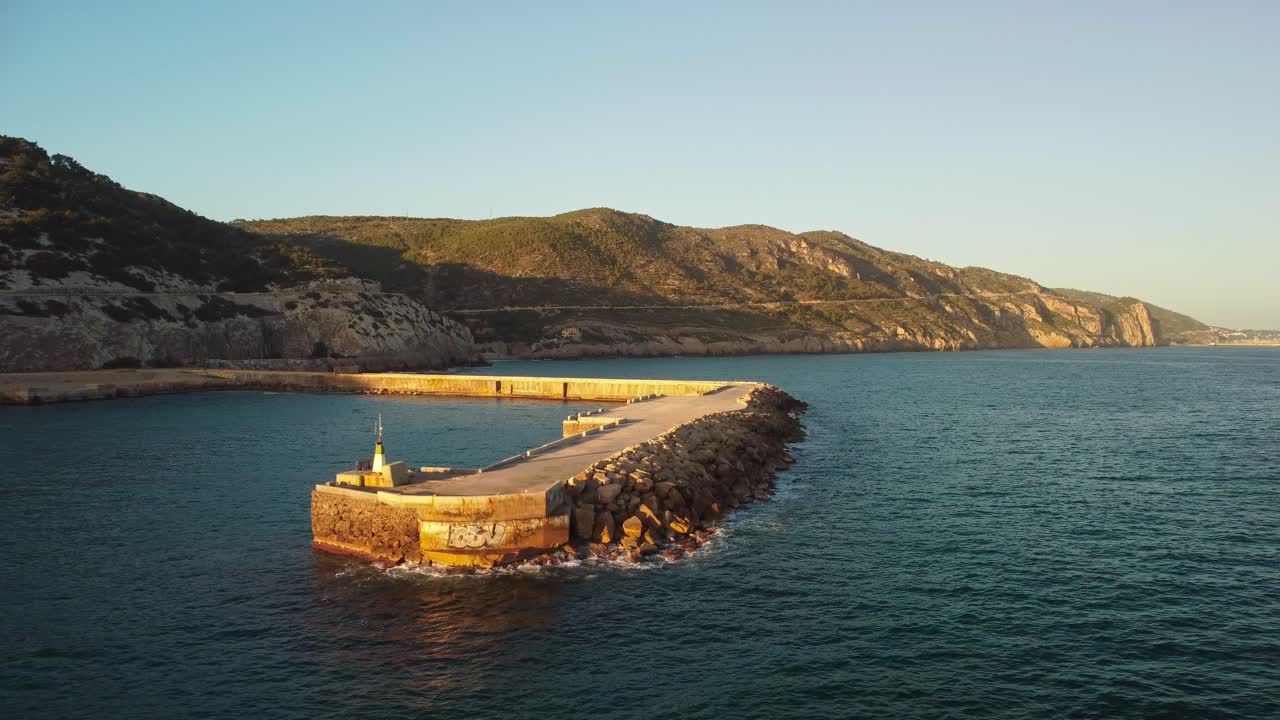 A coastal pier at costa garraf with scenic mountains in the background, aerial view