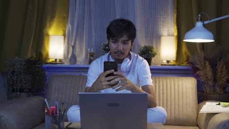 el hombre que envía mensajes de texto en el teléfono en casa por la noche está decepcionado.