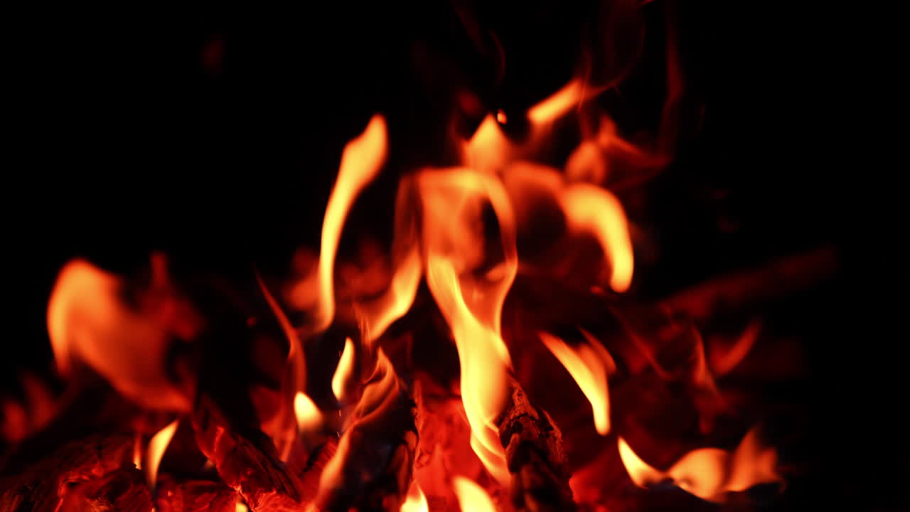 Falò che si sta spegnendo nell'oscurità. Scintille luminose si alzano dal fuoco da campo. Primo piano.