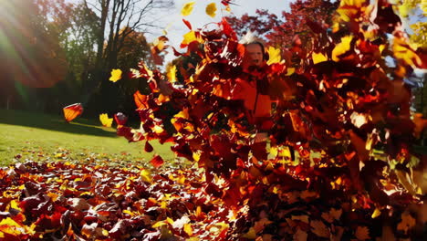 a young girl joyfully playing with colorful autumn leaves in a park