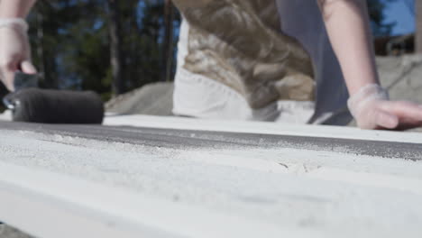 close up of paint brush roller, painting white pre painted planks slow