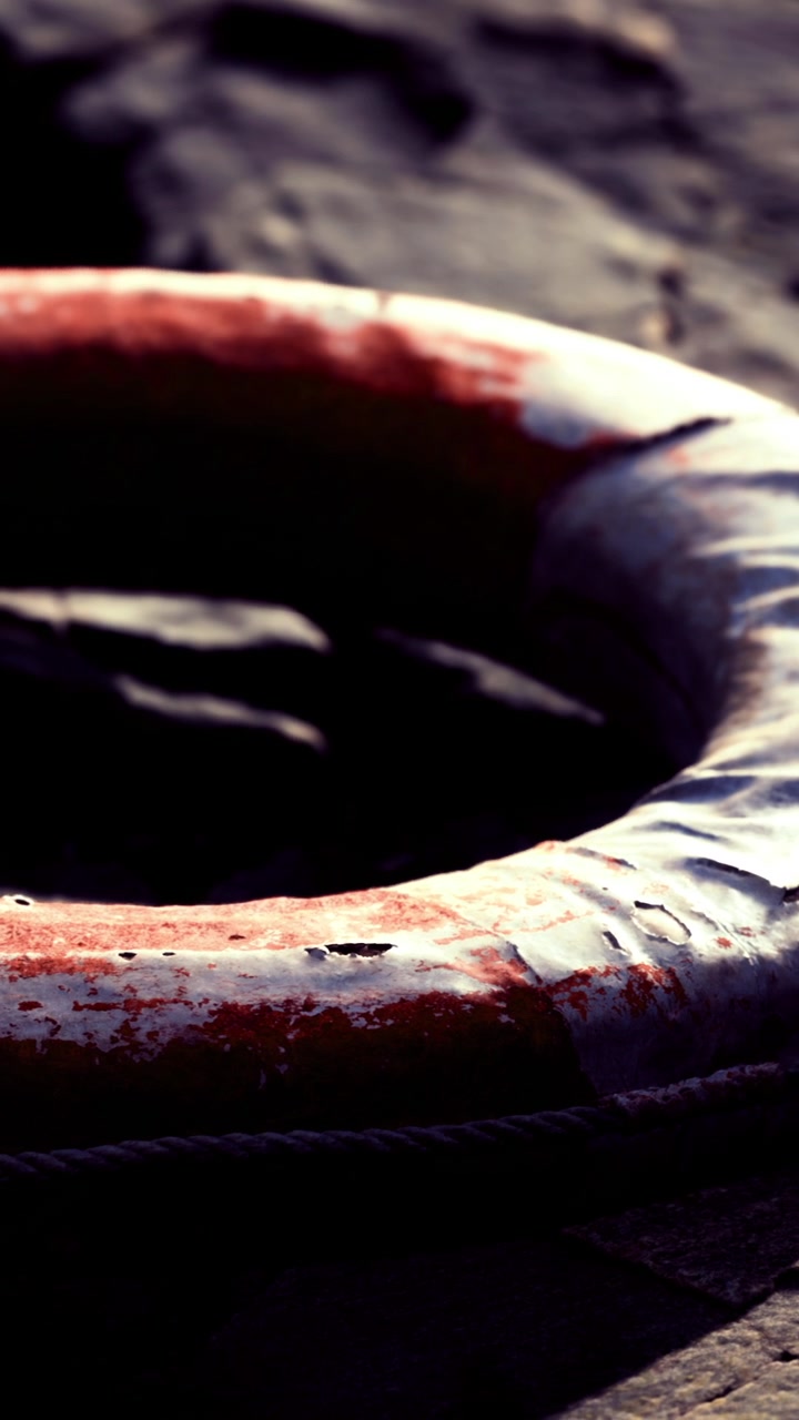 Life ring resting on a rocky surface near water in the afternoon sun