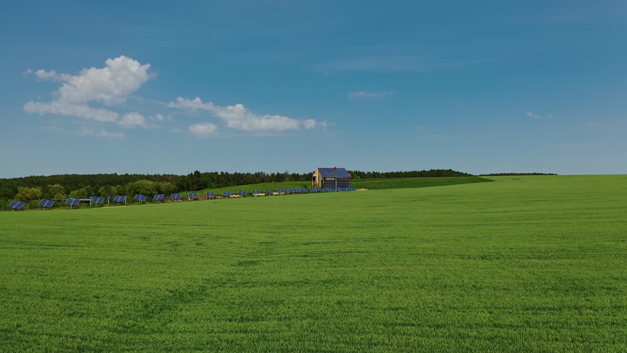 Solar farm on green field. Flying over the field of agricultural plants to the modern complex with many solar panels. Alternative energy. Aerial view.