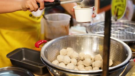 vendedor preparando albóndigas en un puesto de mercado flotante