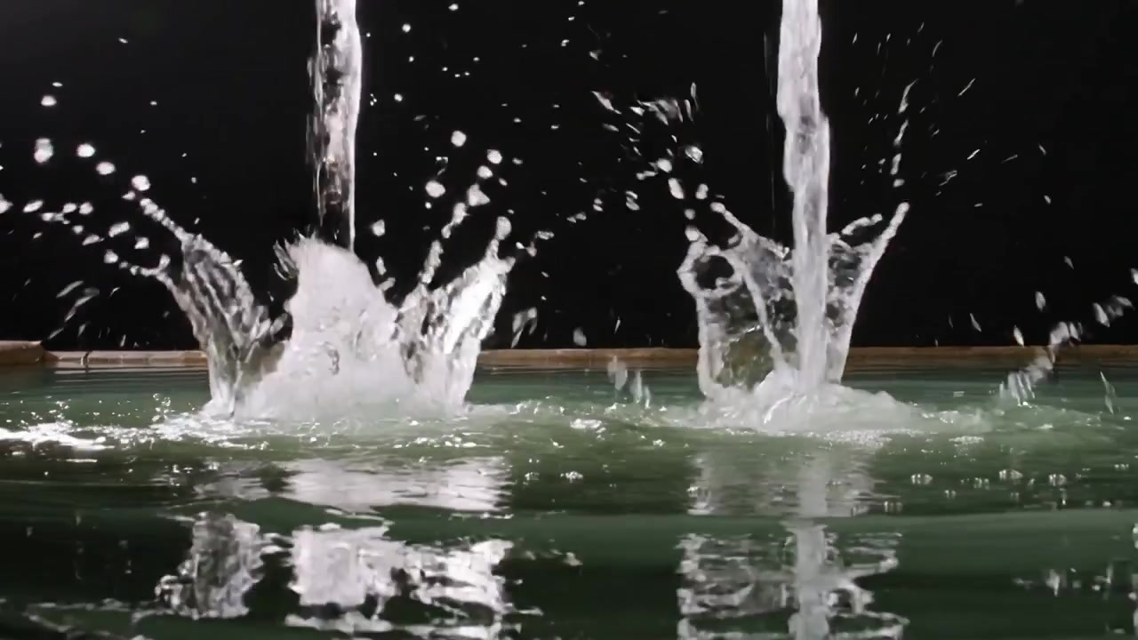 Due colonne d'acqua che cadono e colpiscono una vasca verde poco profonda in studio, formando schizzi a corona e goccioline.