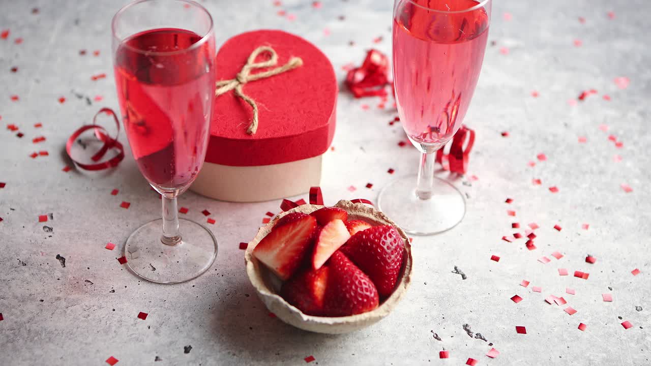 신선한 딸기와 하트 모양의 선물을 넣은 장미 샴페인 잔