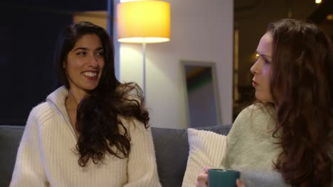 Two-Female-Friends-Sitting-On-Sofa-At-Home-Or-In-Bar-Or-Cafe-Talking-And-Drinking-Coffee-Together-1