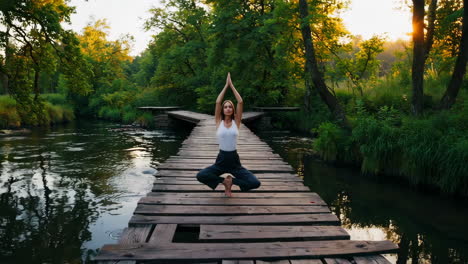 woman practicing yoga and meditation on a tranquil boardwalk in nature