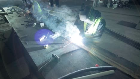 professional welders are working in the factory wearing safety equipment. metalwork manufacturing, industrial process.