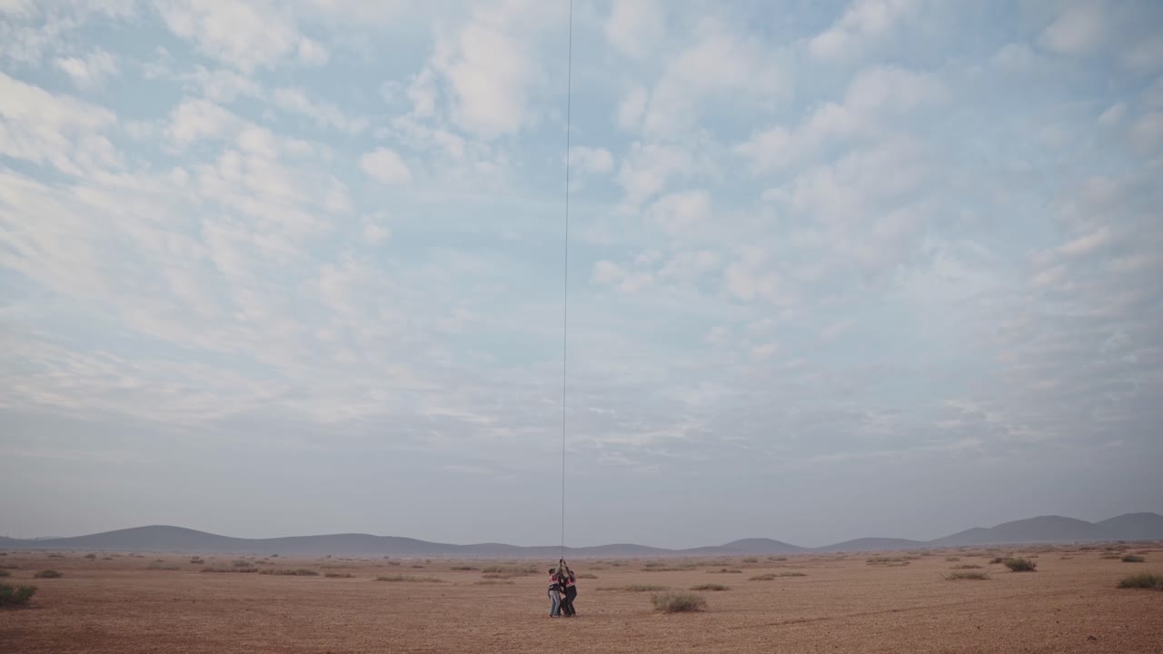 grupo de personas tirando de un globo aerostático con una cuerda en el desierto de marruecos