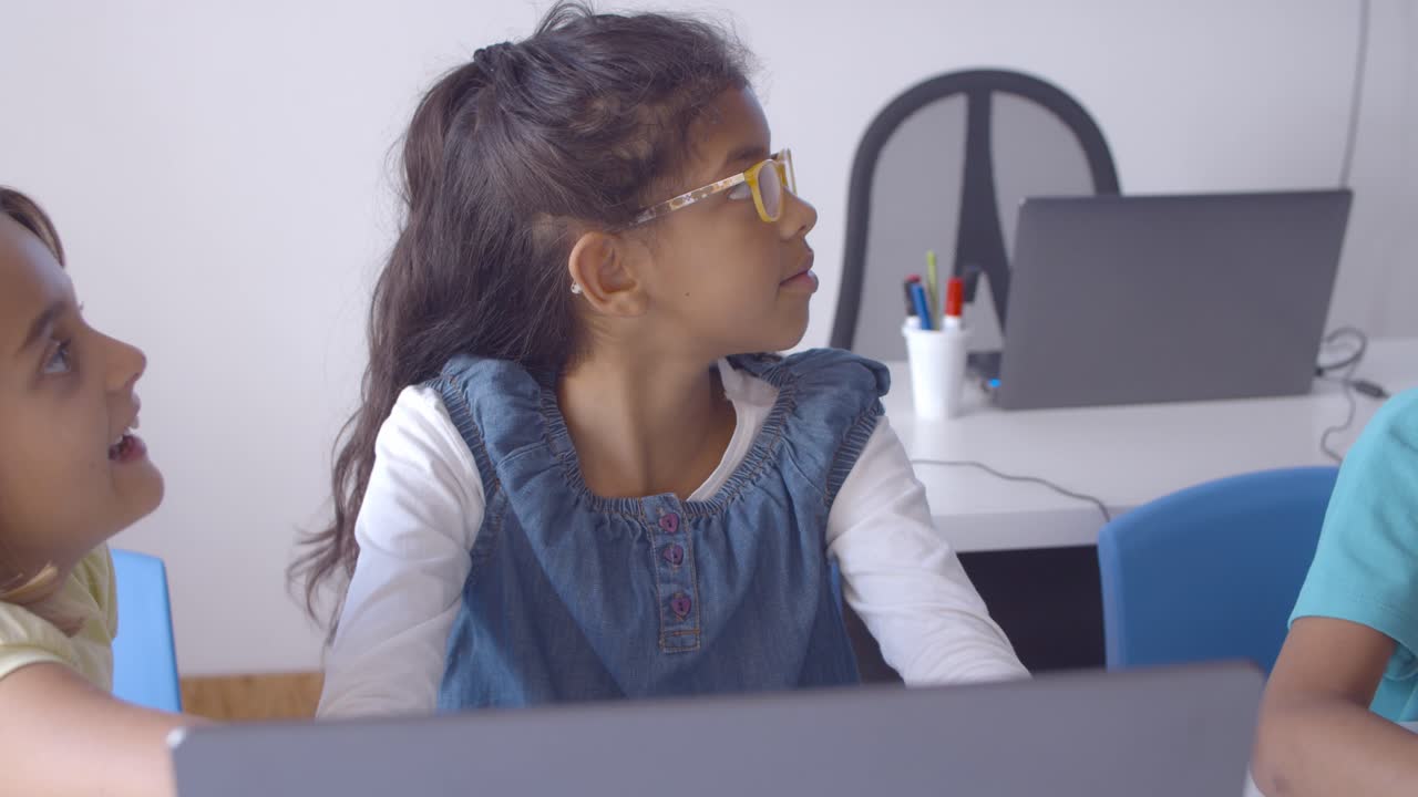 estudiante enfocada con gafas usando una computadora portátil en clase